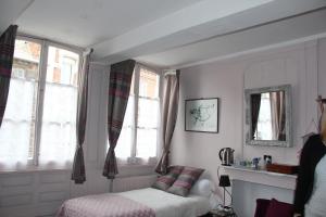 een slaapkamer met een bed en 2 ramen bij Les Capucines in Abbeville
