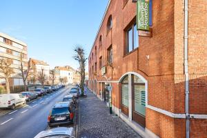 un edificio in mattoni con auto parcheggiate sul lato di una strada di Generation Europe Youth Hostel a Bruxelles