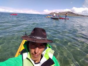 a man in a hat sitting in a kayak in the water at Luquina homestay in Puno