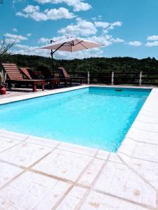 a swimming pool with an umbrella and chairs at Terrazas de mayu in Villa Icho Cruz