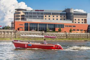 a red boat in the water in front of a building at Qubus Hotel Kraków in Kraków