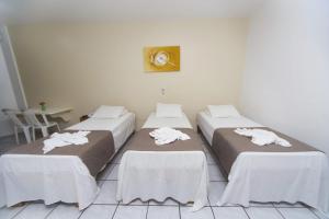 a group of three beds in a room at Hotel Rekinte in Aracaju