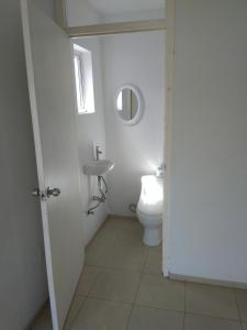 a white bathroom with a toilet and a sink at Yolo Apartment in Willemstad