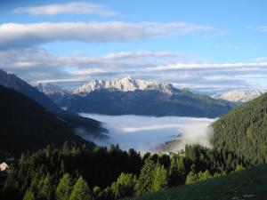 a view of a valley with fog in the mountains at Naschthof in Dobbiaco
