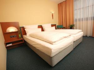 sypialnia z dużym łóżkiem z białą pościelą w obiekcie Transmar Travel Hotel w Bindlach