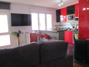 a living room with a couch and a kitchen with red cabinets at Piso en Gijon cerca de PLAYA del ARBEYAL in Gijón