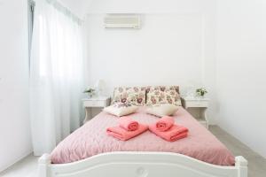 biała sypialnia z różowymi ręcznikami na łóżku w obiekcie Apartments Klery - Studios 5 w mieście Nausa