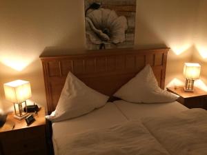 a bedroom with a bed with pillows and two lamps at Seevilla West am Großen Plöner See in Ascheberg +44 photos