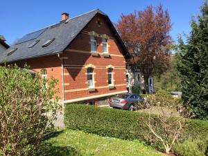 een bakstenen huis met een auto ervoor geparkeerd bij Wohlfühl-Ferienwohnungen König in Bad Elster