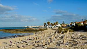 une plage avec des chaises et des parasols et l'océan dans l'établissement Lima waikiki beach, à Corralejo