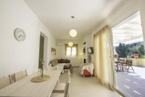 una sala da pranzo e un soggiorno con orologio a parete di Miltiadis Apartments Spiti Miltiadis ad Agios Georgios Pagon