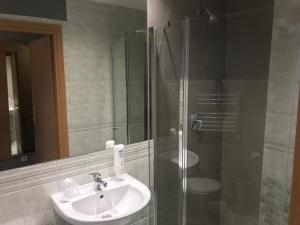 Un baño con lavabo y ducha de cristal. en Hotel Dunajec, en Zgłobice
