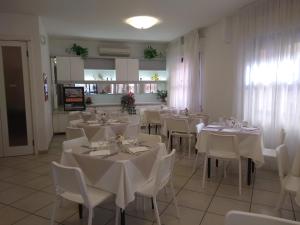 a dining room with white tables and white chairs at Hotel La Bella Vita in Rimini