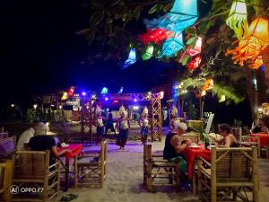 un grupo de personas sentadas en las mesas de noche en Eco Lanta Hideaway Beach Resort, en Ko Lanta
