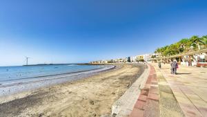 ein Strand mit Menschen, die auf dem Sand und dem Meer spazieren in der Unterkunft Armonía Beach 15 in Arinaga