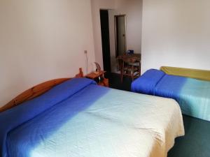 una camera con due letti con lenzuola blu e bianche di ALBERGO SORGENTI DEL PIAVE a Sappada