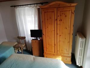 una camera da letto con armadio in legno e TV di ALBERGO SORGENTI DEL PIAVE a Sappada