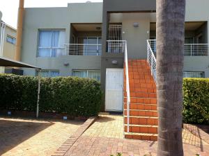 an apartment building with a white door and bushes at D'urban Ridge Self catering Apartment in Cape Town