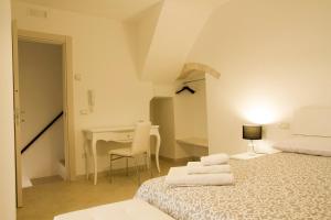 a white bedroom with a bed and a desk at Casa Giannina B&B in Castellana Grotte