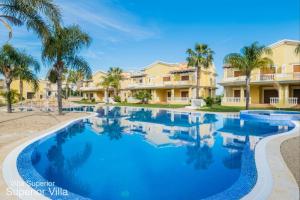 a swimming pool with palm trees and houses at Akivillas Tavira Conceicao in Conceição