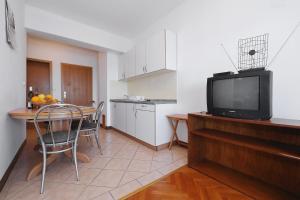a kitchen and dining room with a table and a television at Villa Vukic in Vrsi