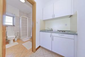 a white bathroom with a toilet and a sink at Villa Vukic in Vrsi