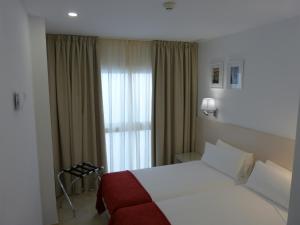 Habitación de hotel con cama y ventana en Apartamentos Patagonia Sur en Cádiz