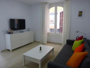 a living room with a couch and a tv and a table at Apartamentos Patagonia Sur in Cádiz