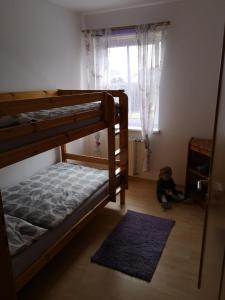 Un niño pequeño sentado en el suelo en una habitación con literas en Eibenberger, en Stubenberg