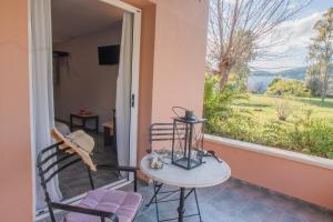 een terras met twee stoelen, een tafel en een raam bij Tellis Holiday Rooms in Moraitika