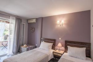 een slaapkamer met twee bedden en een raam bij Tellis Holiday Rooms in Moraitika