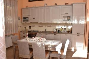 a kitchen with white cabinets and a table with chairs at Il Corallo Rosso in Giardini Naxos