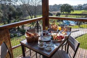 a table with bread and baskets of food on a balcony at Quintinha do Periqueiro in Castelo do Neiva