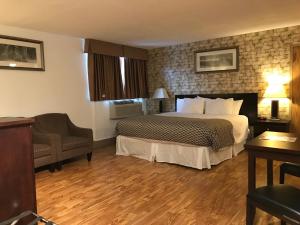 ein Hotelzimmer mit einem Bett und einem Stuhl in der Unterkunft Stonebridge Hotel in Fort McMurray