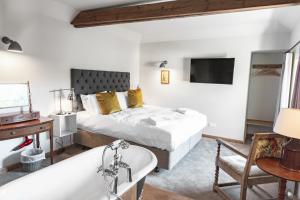 a bedroom with a bed and a tub and a sink at Black Horse in Amberley