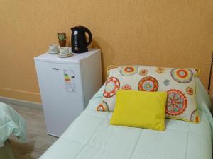 a white bed with a yellow pillow next to a refrigerator at Giova Apart Salta in Salta