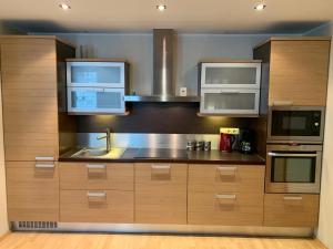 a kitchen with wooden cabinets and stainless steel appliances at Ilmarine Apartment in Tallinn