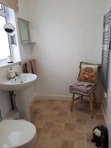 a bathroom with a sink and a toilet and a chair at Forest Farm Papplewick Nottingham - Spacious Self-Contained Rural Retreat! in Papplewick