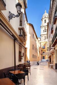 ulica ze stołami i krzesłami oraz wieżą zegarową w obiekcie INMálaga Fresca II w Maladze