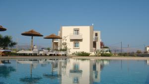 un edificio y una piscina con sillas y sombrillas en Double Bay Beach Hotel en Elafonisos