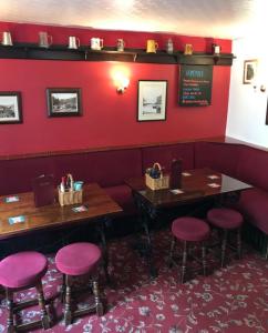 a restaurant with red walls and two tables and stools at The Royal George Staithes in Staithes