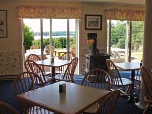 uma sala de jantar com mesas, cadeiras e janelas em Cod Cove Inn em Edgecomb