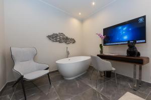 a bathroom with a tub and two chairs and a tv at Clementi Portrait in Rome