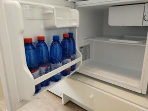 a refrigerator filled with blue bottles of water at Buto nuoma šviesos gatvėje in Telšiai