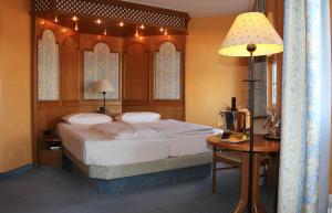 a bedroom with a bed and a table with a lamp at Hotel Spanischer Hof in Gröditz