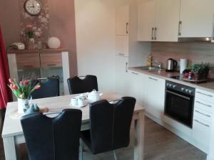 a kitchen with a white table and black chairs at Leichte Brise in Greetsiel