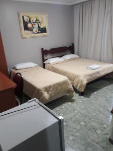 a room with two beds and a tv in it at Hotel Nolasco in Macaé
