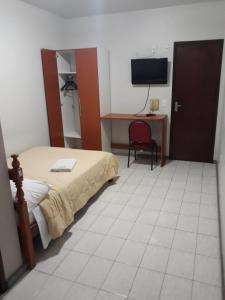 Schlafzimmer mit einem Bett, einem Schreibtisch und einem TV in der Unterkunft Hotel Nolasco in Macaé