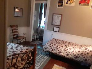 a bedroom with two beds and a chair and a window at Creole Victorian for groups large and small in New Orleans