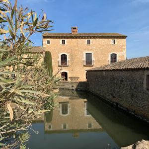 un edificio se refleja en una masa de agua en Hotel Molí de l'Escala en L'Escala